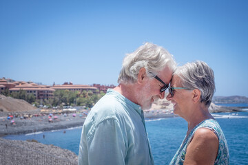 Happy senior couple standing at the sea enjoying summer and sun