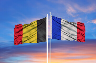 France and Belgium two flags on flagpoles and blue cloudy sky