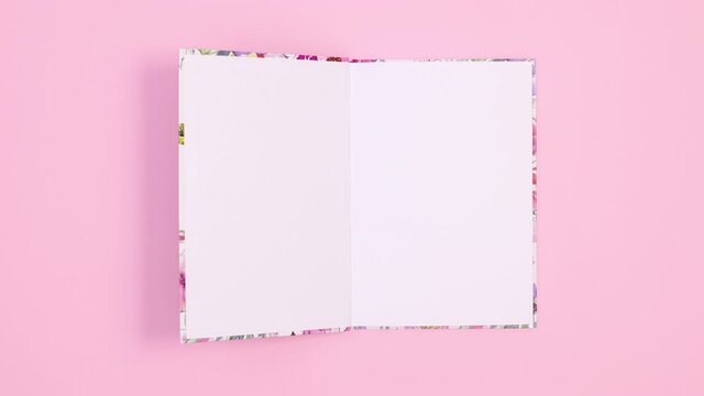 Beautiful floral notebook appear on pastel pink theme and open. Stop motion