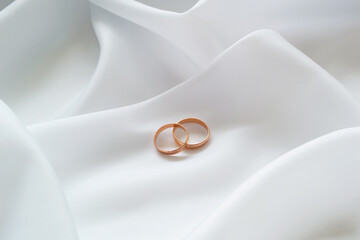 Gold wedding rings on white cloth. Close-up.
