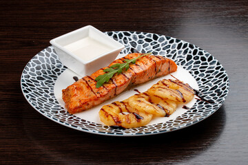 Salmon with cream sauce and grilled pineapple. On a wooden background