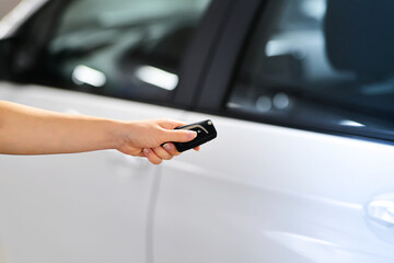 Women's hand presses on the remote control car to lock her car. New technology car keys remote concept. 