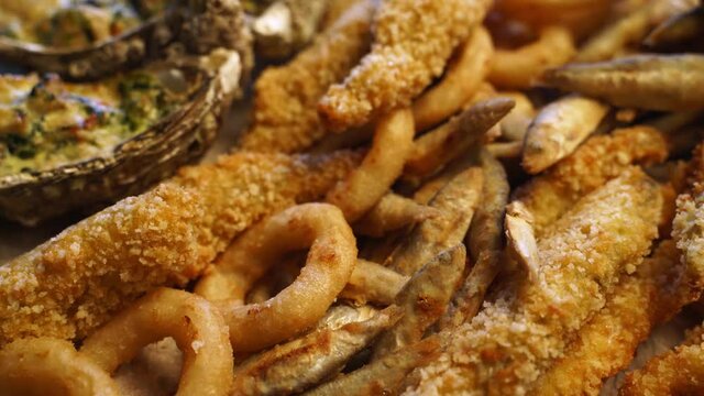 Served deep fried fish mix food set composition. Cook made squid rings, sprat, gobies, oysters on a tray in luxury asian restaurant. Delicious snacks and sauces in cafe.