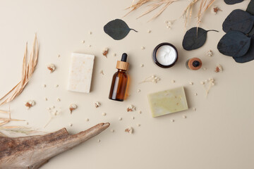 Cosmetic skin care products with soap and flower on pastel beige background. Flat lay, copy space.