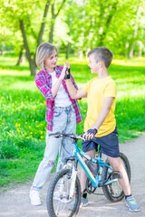 Obraz premium Mom and her young son give high five while cycling in the park