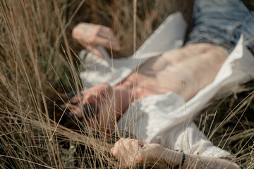 the guy lies on the grass in a shirt with an open torso
