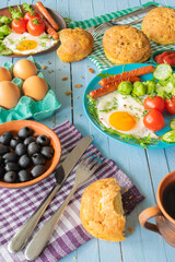 composition of rustic breakfast, eggs and sausage with vegetables, roll and coffee, wooden background
