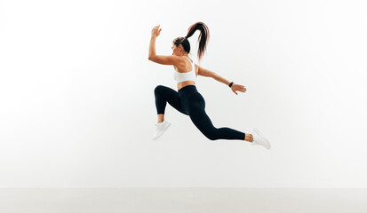Fototapeta na wymiar Female athlete running and jumping against white backgroung
