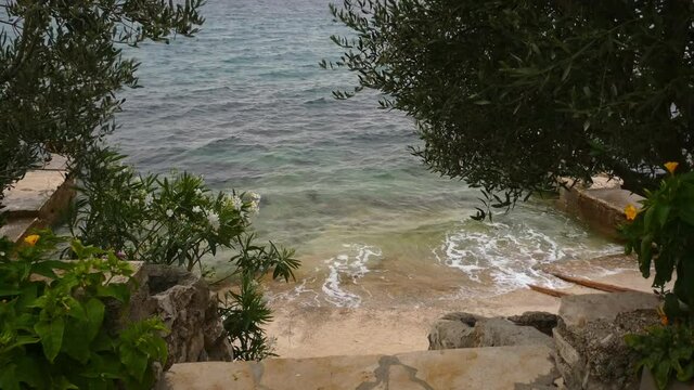 Soothing waves crashing on beautiful stone stairs headed to sea waver, surrounded by plants