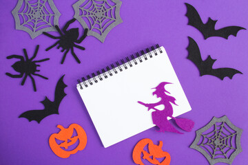 Composition  for Halloween with white notebook, decorative witch, spiders, pumpkins, spider webs...