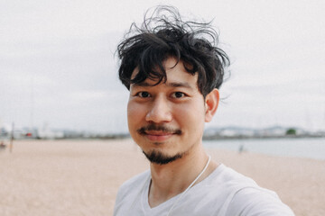 Happy Asian man selfie himself relaxed on the beach. Concept of summer holiday.