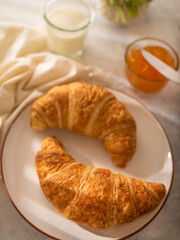 Two croissants, orange jam, milk. White silk tablecloth. Breakfast. Low angle view. Close-up. Careful viewing. Restaurant, hotel, cafe, home cooking, recipe book, dish design.