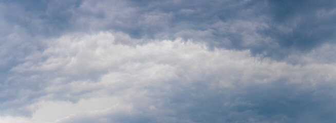 White curly cloud in the sky surrounded by dark clouds, panorama
