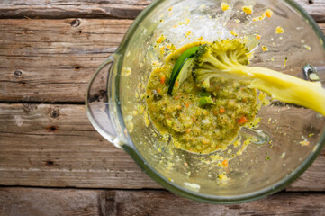 Vegetable smoothie. Cooking process. Cooked raw vegetables in a large glass bowl for mixing. Wooden texture. Restaurant, cafe, advertisement, poster, banner. Low angle view.