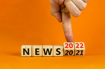 2022 News new year symbol. Businessman turns a wooden cube and changes words 'News 2021' to 'News 2022'. Beautiful orange background, copy space. Business, 2022 News new year concept.