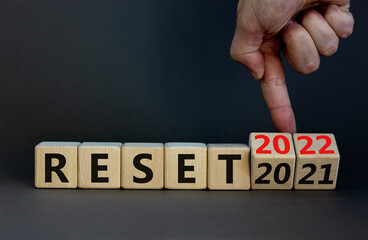 2022 reset new year symbol. Businessman turns wooden cubes and changes words 'Reset 2021' to 'Reset 2022'. Beautiful grey background, copy space. Business, 2022 reset new year concept.