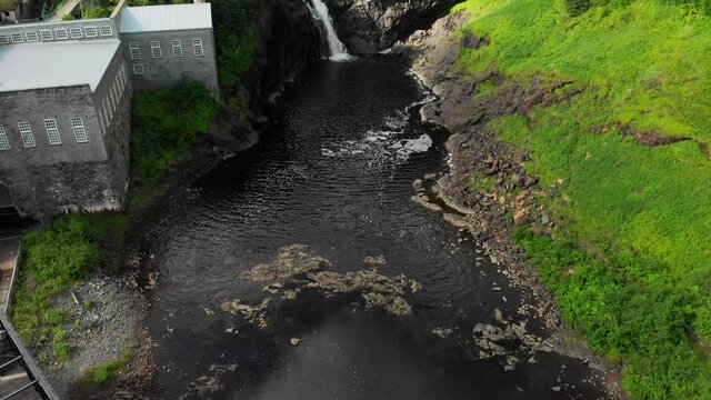 Aerial, wide, waterfall in Val-Jalbert, Quebec, tilt up and approach.
