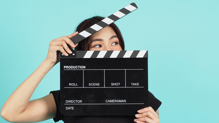 Asian Woman holding black clapperboard on mint or Tiffany Blue background.