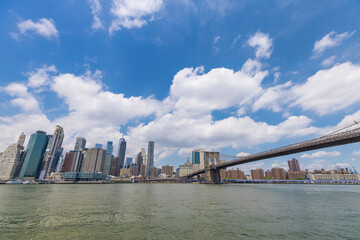 Unique shape summer clouds float over the Lower Manhattan skyscraper and Brooklyn Bridge along the East River on June 20, 2021 in the Brooklyn Borough of New York City NY USA.