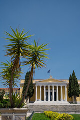 Fototapeta na wymiar Front view of the Zappeion Hall in the National Gardens of Athens. Blue sky. Green trees. Classical architecture.