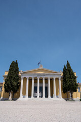 Fototapeta premium Front view of the Zappeion Hall in the National Gardens of Athens. Blue sky. Green trees. Classical architecture.