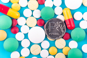 metal coin ruble surrounded by tablets and pills