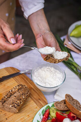 Preparing baguette with cottage cheese. Woman serving vegetarian food