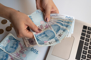 in woman's hands
hundred Turkish lira.
computer keys in the background.
concept of fraud, internet...