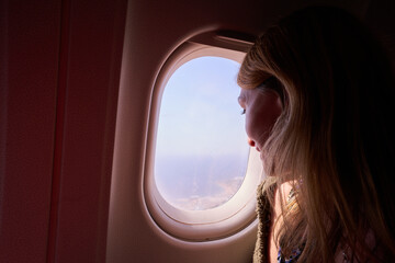 Fototapeta na wymiar girl looking out the plane window
