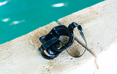 A diving mask that lies on the rocks and next to the pool