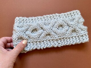hand touching a knitted cable headband 