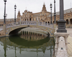 An ornate bridge over a moat fronting the Plaza de Espana historical building in Seville, Spain - obrazy, fototapety, plakaty