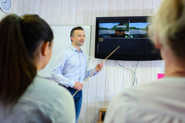 driving instructor pointing at board in a classroom