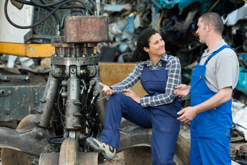 Fototapeta na wymiar scrap yard workers talking next to grabber hook