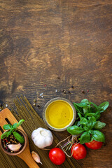 Ingredients for italy cuisine. Spinach spaghetti, herbs, spices, olive oil and tomatoes on a rustic table. Top view flat lay background. Copy space.