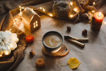 Fototapeta na wymiar Autumn still life details in cozy home interior with a cup, candles, plaid. Hygge, Halloween and Thanksgiving concept 