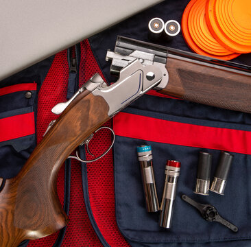 Double-barreled vertical shotgun and cartridges for it on a sports shooting vest. Shooting sport poster concept. Clay target plates for shooting with rifle on wooden back