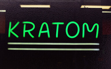 Fototapeta na wymiar Kratom or Mitragyna speciosa Neon Sign in Window of Smoke Shop