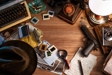 Private detective's desk, noir still life with a vintage phone, typewriter, lamp, gun and retro...
