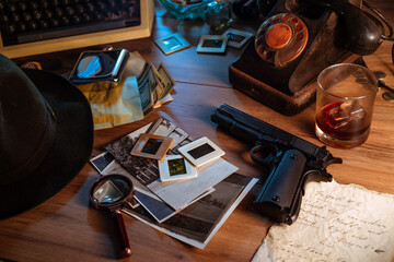 Private detective's desk, noir still life with a vintage phone, typewriter, lamp, gun and retro photos