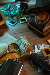 Private detective's desk, noir still life with a vintage phone, typewriter, lamp, gun and retro...