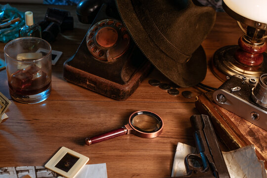 Private detective's desk, noir still life with a vintage phone, typewriter, lamp, gun and retro photos