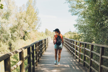 Woman walking across a bridge on a rural footpath.