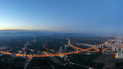 Night city during fog with glowing roads view from above.