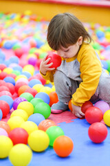 Creative development of children. The kid plays with colored balls in the children's development center.
