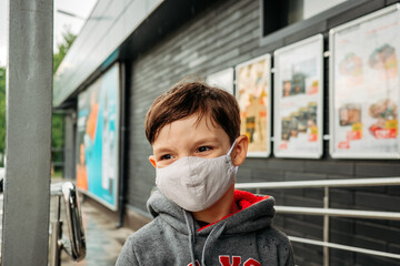 A boy in a protective mask enters the supermarket. Protecting a child from covid-19 coronavirus in a supermarket.