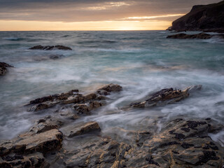Fototapeta na wymiar The sun setting over slate ledges on the north Cornwall coast