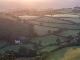 Sunrise on a misty morning over the rolling hills and farmland of Dartmoor