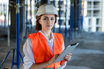 Portrait of beautiful female architect who stands idly and smiles against the background of...