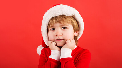 Christmas time. Little boy in Santa costume. Cute child in Santa hat. New Year's holidays.